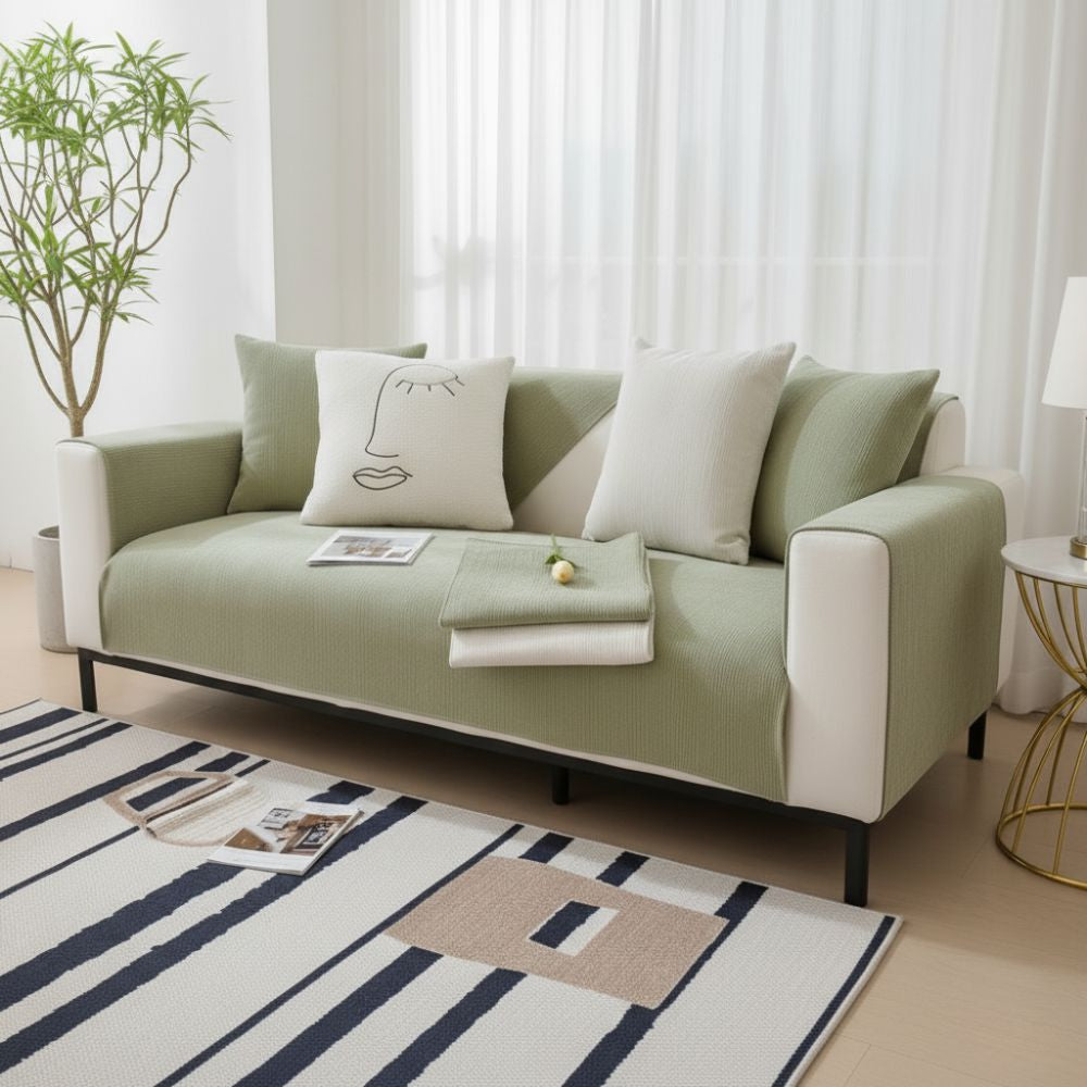 Light sage green Morandi Chenille sofa cover on three-seat sofa in modern living room with striped rug
