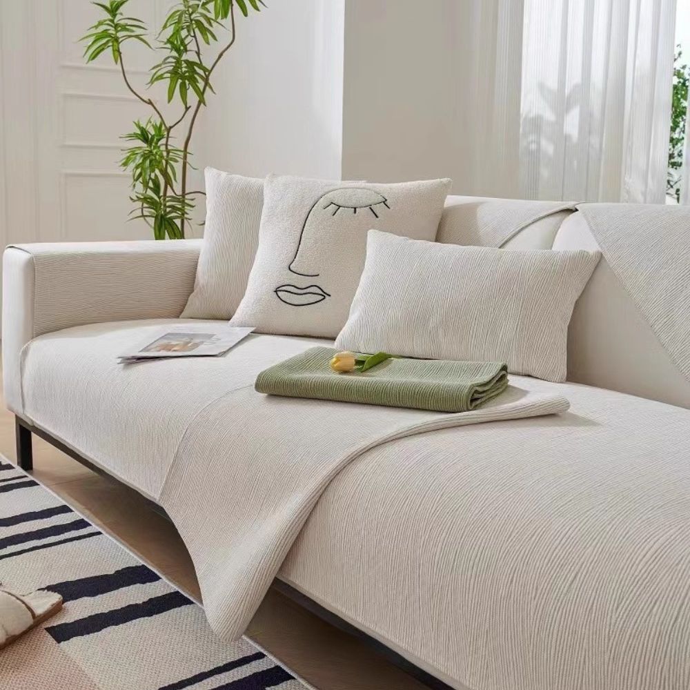 Cream ribbed sofa cover on white sofa with face cushions and folded sage green cover as accent