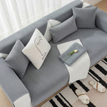 Top-down view of grey morandi chenille sofa cover with decorative face pillow and white tulip flower