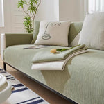 Close view of sage green sofa cover with cream reverse side folded, yellow tulip on top