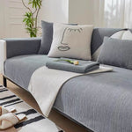 Dark grey sofa cover with cream accent piece, face cushion and tulip flower on sofa