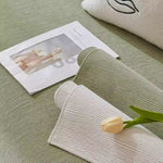 Sage green and cream morandi chenille sofa covers layered on sofa with tulip flower and magazine styling